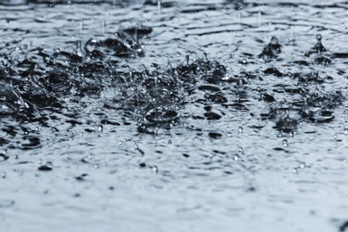 Photo of Heavy rain falling down into puddle outdoors