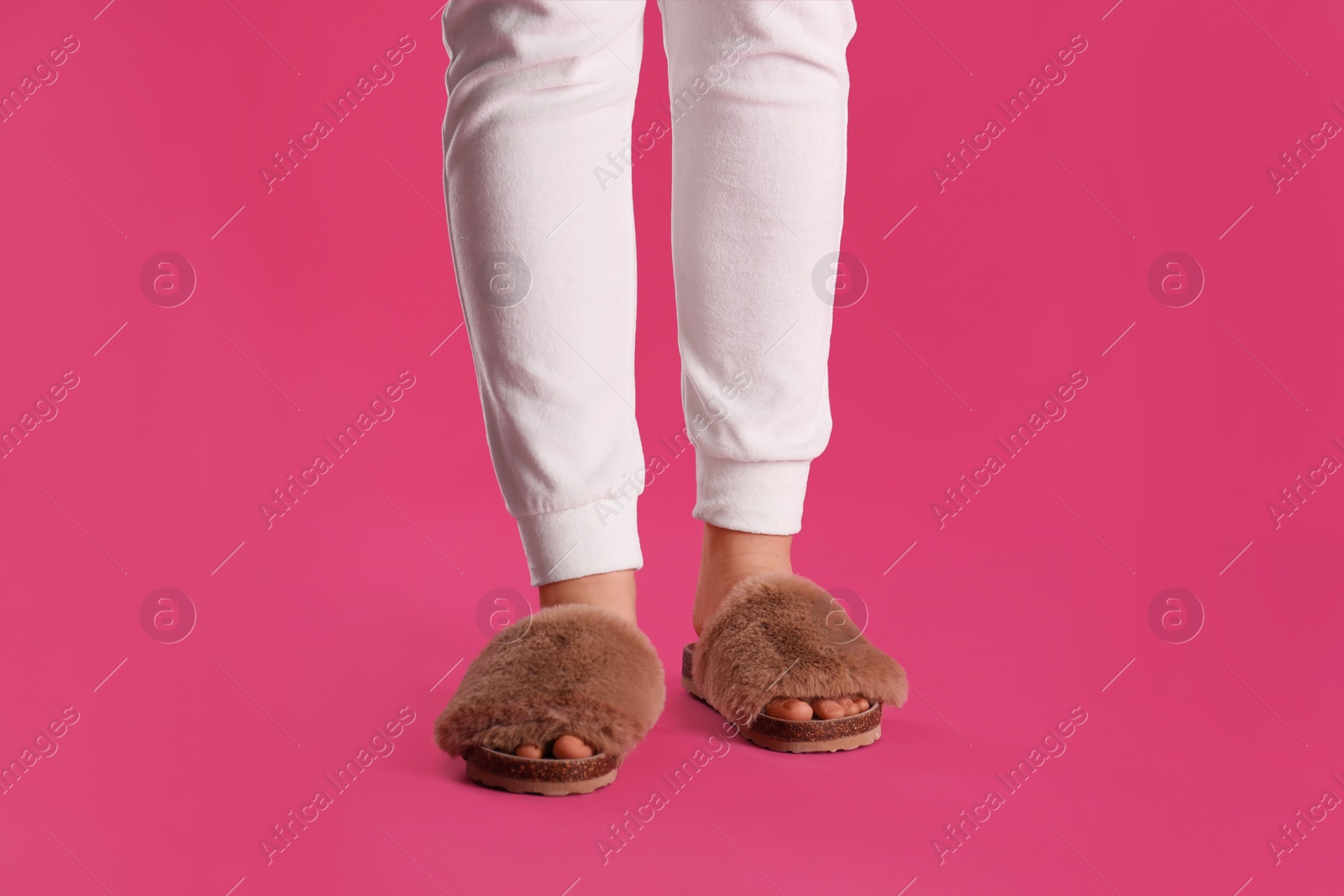 Photo of Woman in fluffy slippers on pink background, closeup