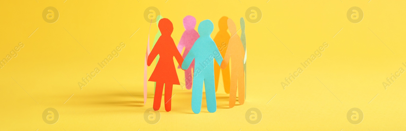 Image of Paper human figures making circle on yellow background, banner design. Diversity and Inclusion concept