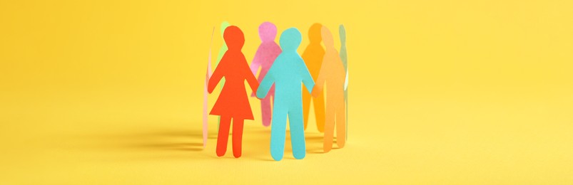 Paper human figures making circle on yellow background, banner design. Diversity and Inclusion concept