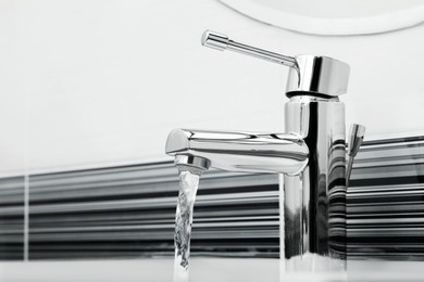 Image of Stream of water flowing from tap in bathroom