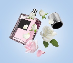 Bottle of perfume and roses in air on light blue background. Flower fragrance