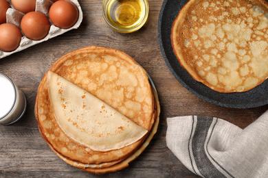 Photo of Flat lay composition with thin pancakes on wooden table