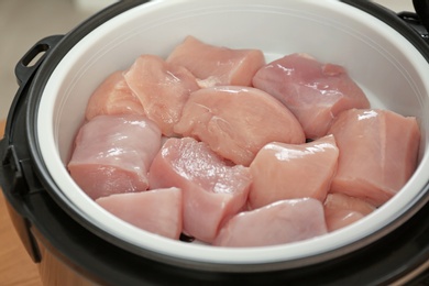 Fresh cut chicken in modern multi cooker, closeup