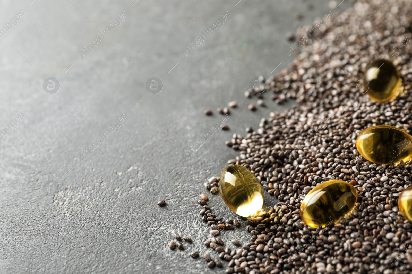 Photo of Chia oil capsules with seeds on grey background. Space for text