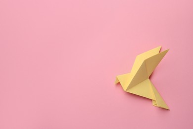 Photo of Beautiful yellow origami bird on pink background, top view. Space for text