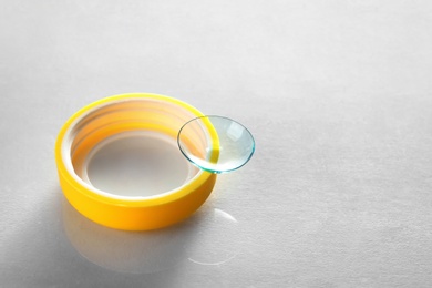 Photo of Plastic cap with contact lens on light background
