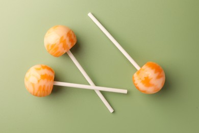 Tasty lollipops on green background, flat lay