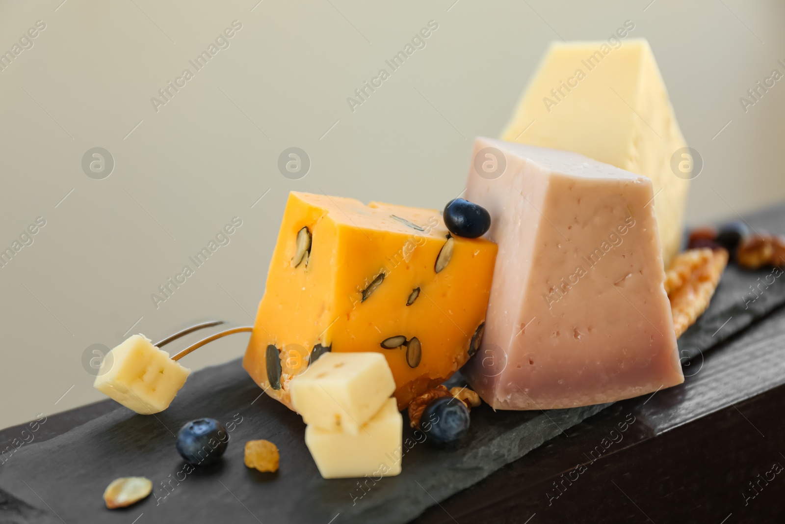 Photo of Different types of delicious cheeses on slate plate, closeup