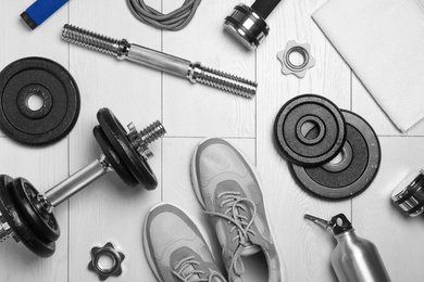 Photo of Gym equipment and shoes on wooden floor, flat lay