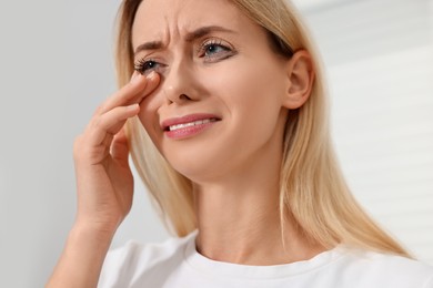 Sad woman with smeared mascara crying indoors, closeup