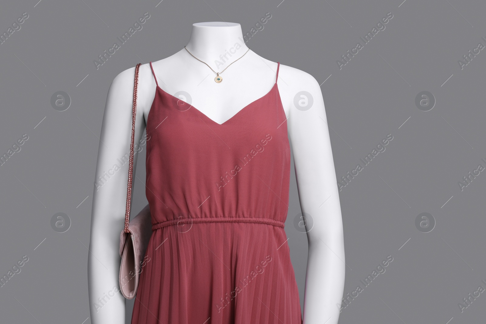 Photo of Female mannequin with necklace and bag dressed in stylish red dress on grey background