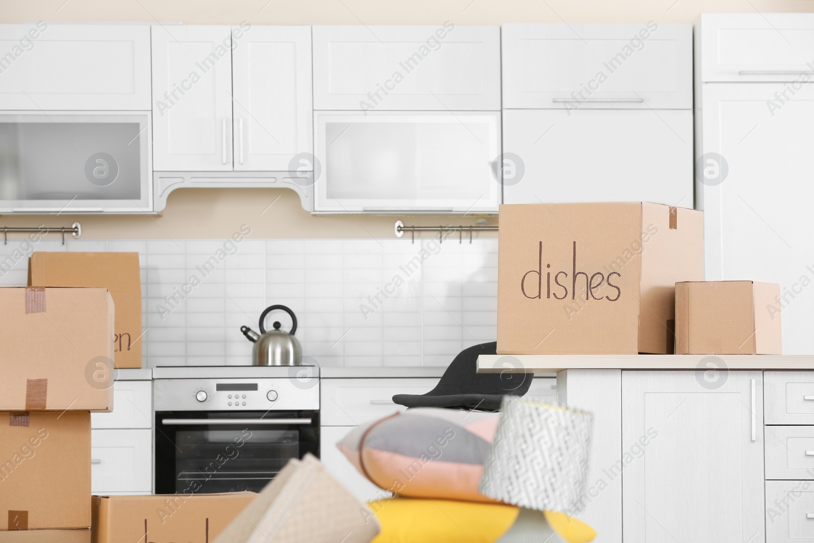 Photo of Cardboard boxes and household stuff in kitchen. Moving day