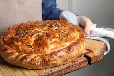 Photo of Woman holding tasty homemade pie indoors, closeup