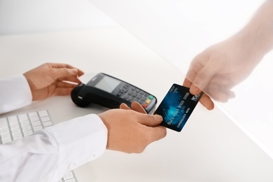 Photo of Man giving credit card to teller at cash department window, closeup