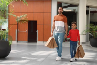 Photo of Family shopping. Happy father and son with purchases in mall