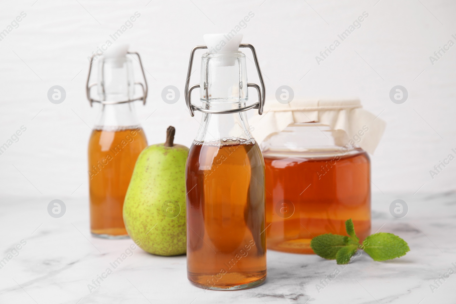 Photo of Tasty kombucha, pear and mint on white marble table