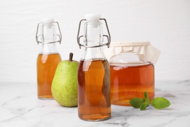 Photo of Tasty kombucha, pear and mint on white marble table