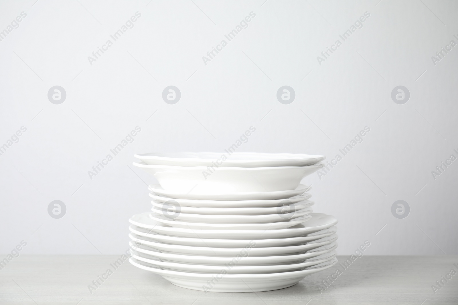 Photo of Stack of clean plates on table against white background. Space for text