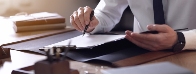 Image of Male lawyer working at table in office, closeup. Banner design