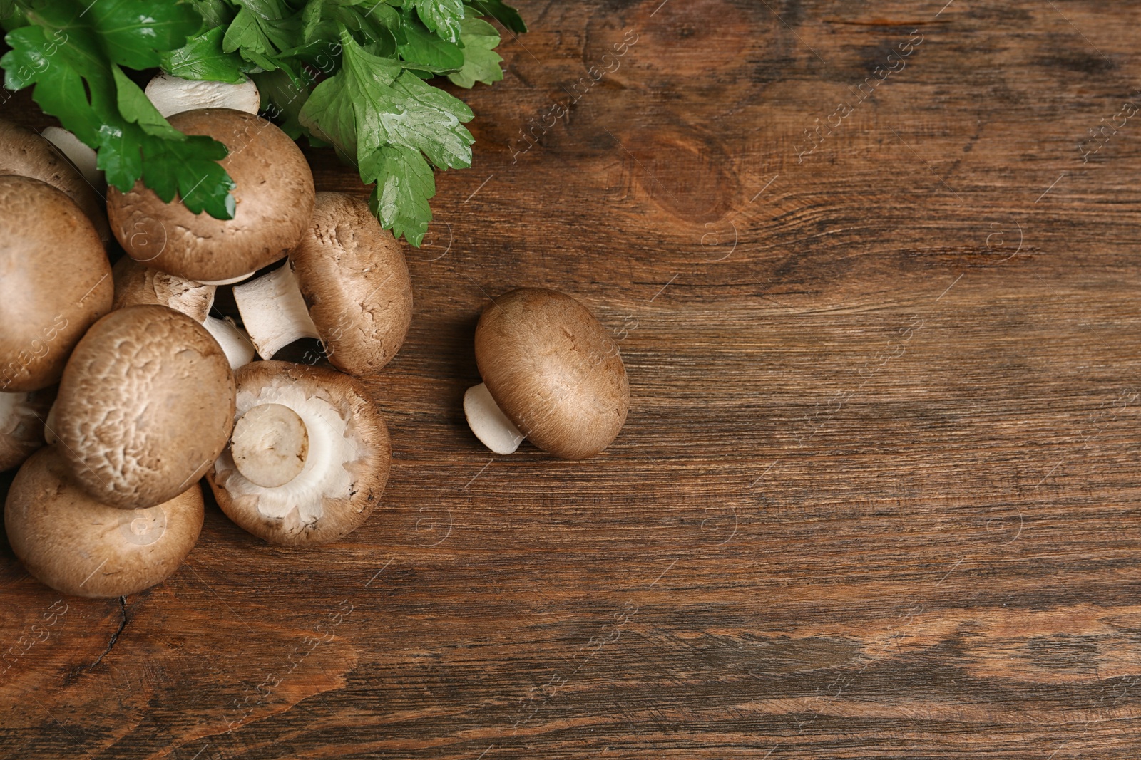 Photo of Fresh champignon mushrooms on wooden background, top view with space for text