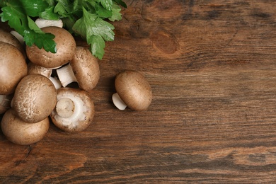 Photo of Fresh champignon mushrooms on wooden background, top view with space for text