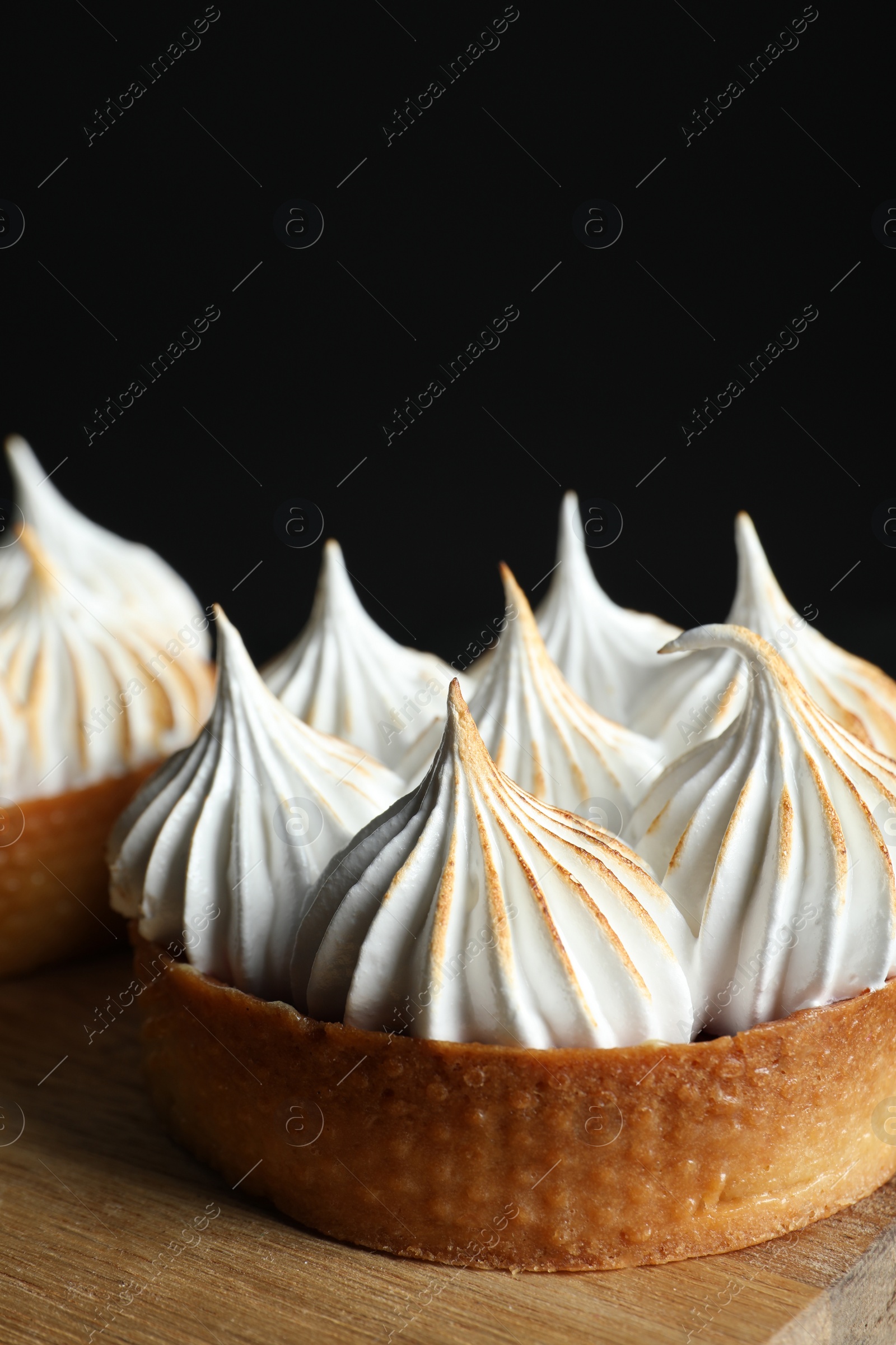 Photo of Tasty dessert. Tartlets with meringue on wooden table, closeup