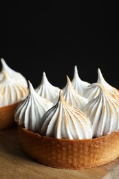 Photo of Tasty dessert. Tartlets with meringue on wooden table, closeup