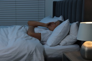 Photo of Woman suffering from headache in bed at night