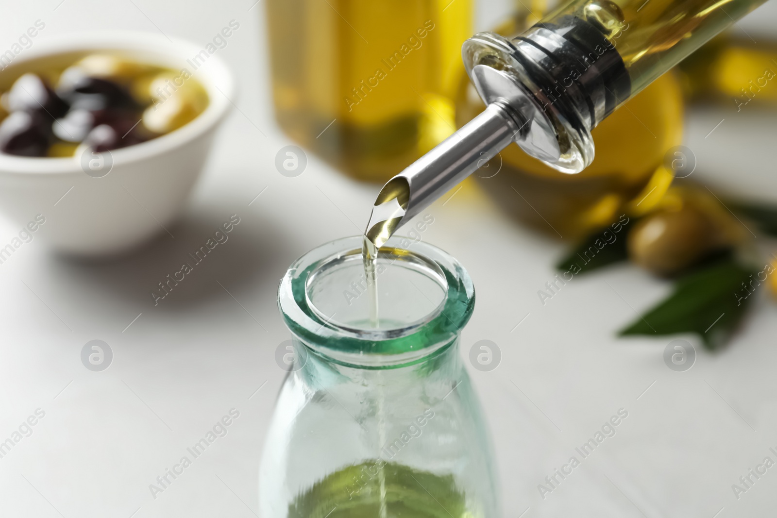 Photo of Pouring fresh olive oil into bottle on table