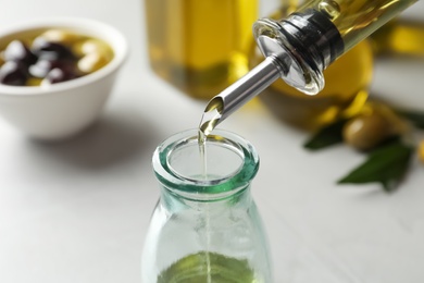 Pouring fresh olive oil into bottle on table