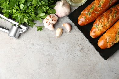 Photo of Plate of bread loaves with garlic and herbs on grey table, flat lay. Space for text