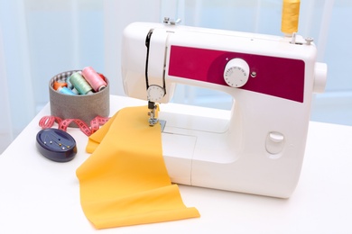 Photo of Modern sewing machine on table near window indoors