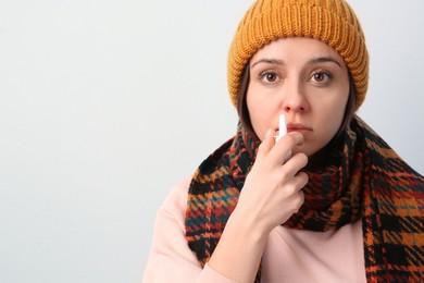 Photo of Woman using nasal spray on beige background. Space for text
