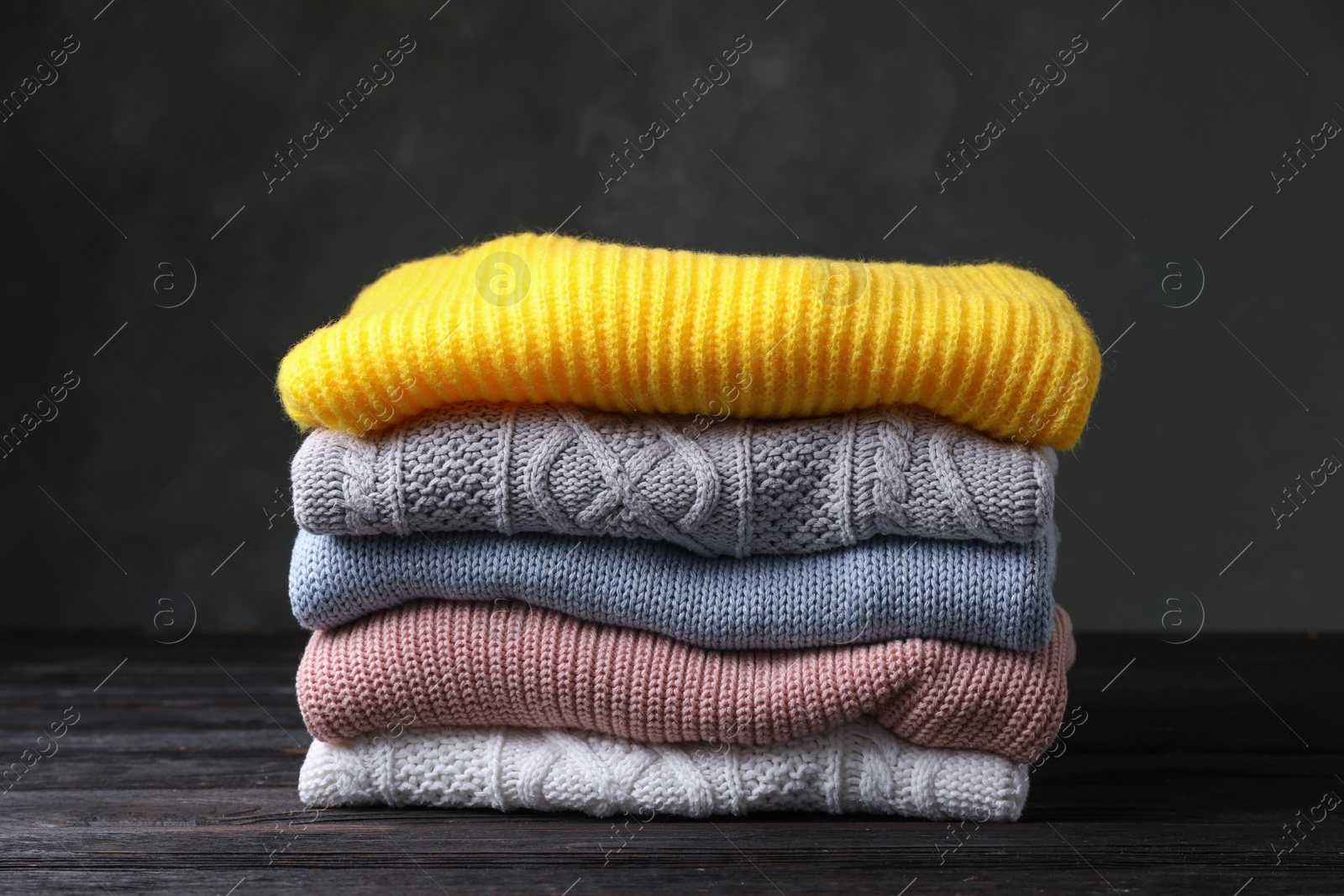 Photo of Stack of folded knitted sweaters on table