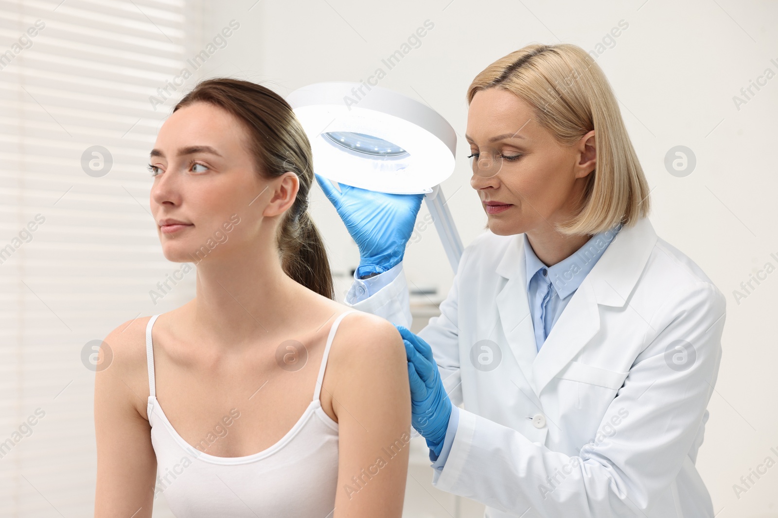 Photo of Dermatologist examining patient under lamp in clinic