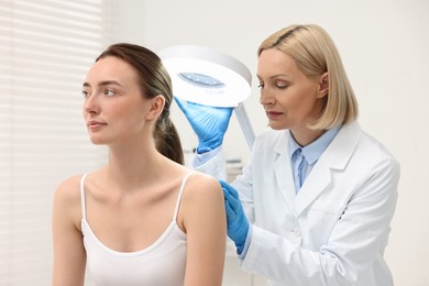 Dermatologist examining patient under lamp in clinic