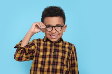Photo of Cute African-American boy with glasses on turquoise background