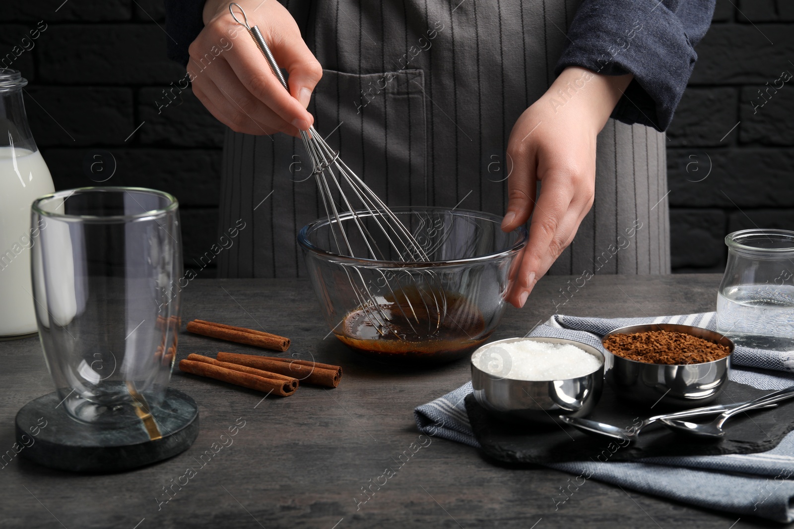 Photo of Woman whipping cream for dalgona coffee at grey table, closeup