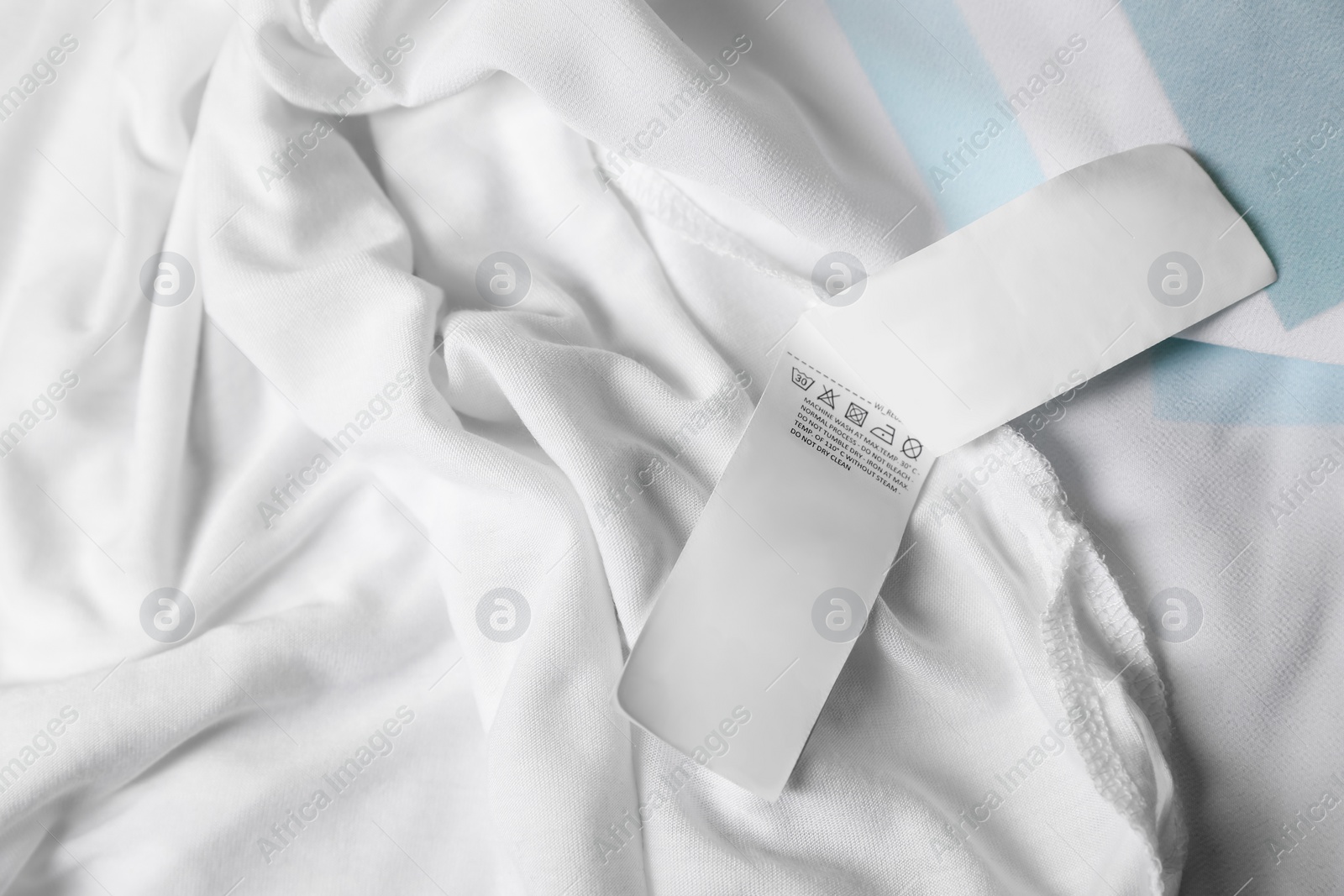 Photo of Clothing label on beautiful white garment, top view