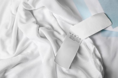 Photo of Clothing label on beautiful white garment, top view