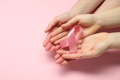 Photo of Breast cancer awareness. Women holding pink ribbon on color background, top view. Space for text