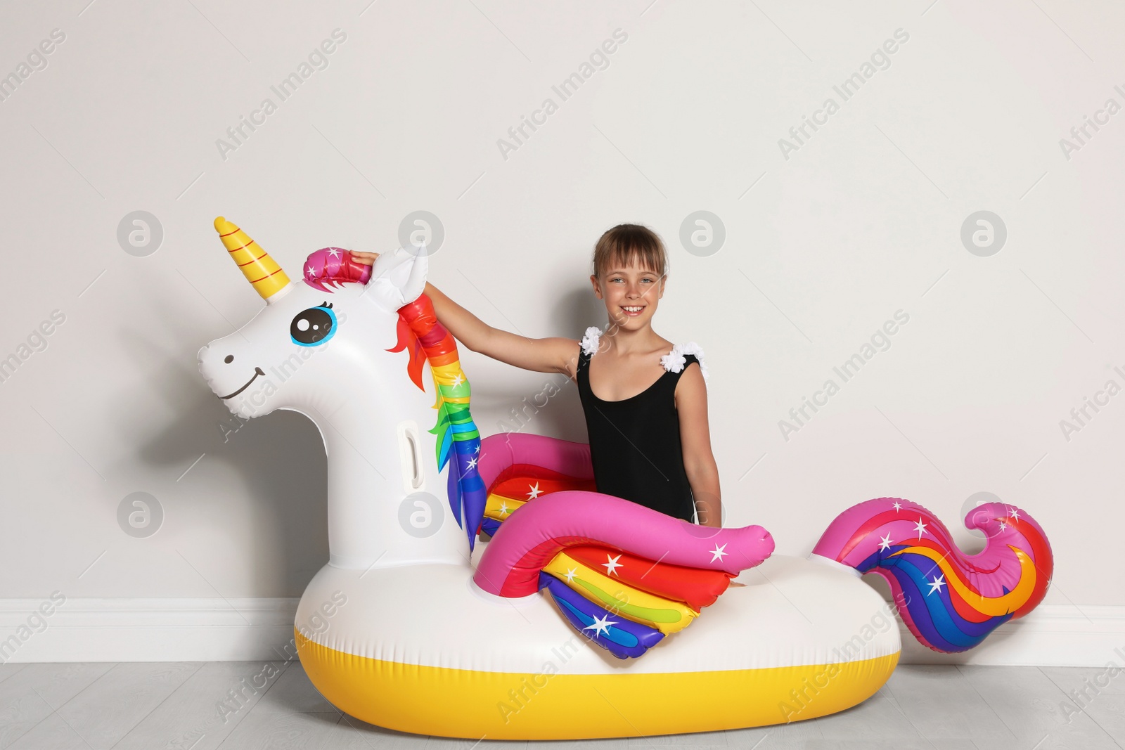 Photo of Cute little girl on bright inflatable ring near light wall