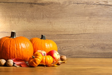 Photo of Composition with ripe pumpkins and autumn leaves on wooden table, space for text. Happy Thanksgiving day
