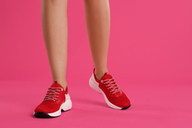 Photo of Woman wearing sneakers on pink background, closeup