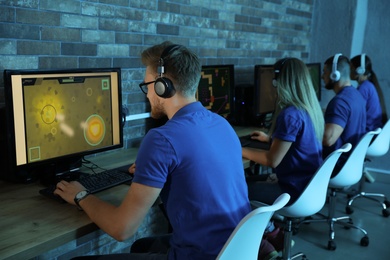Photo of Man playing video game in internet cafe