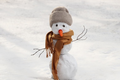 Photo of Funny snowman with scarf and hat outdoors