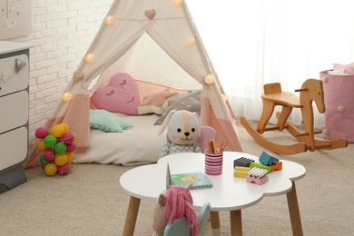 Photo of Cute child's room interior with toys and play tent