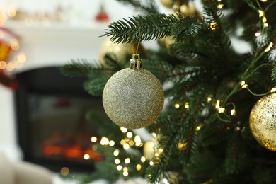 Photo of Beautiful Christmas ball hanging on fir tree branch in room, closeup. Space for text