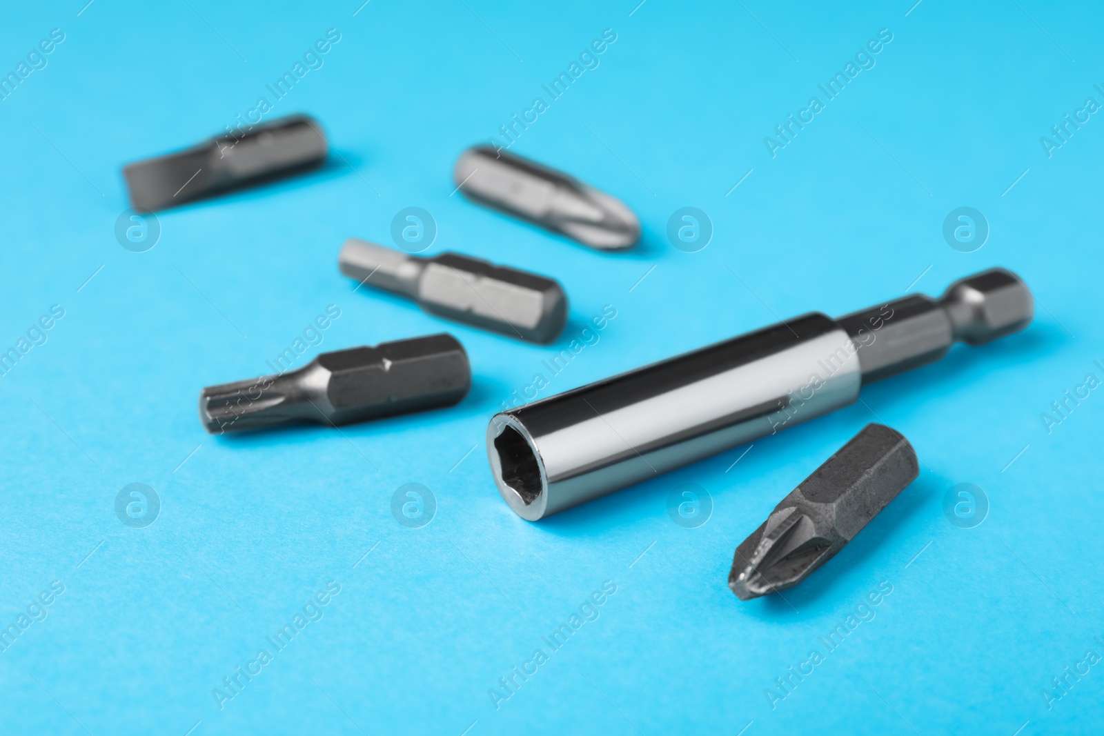 Photo of Different drill bits on light blue background, closeup